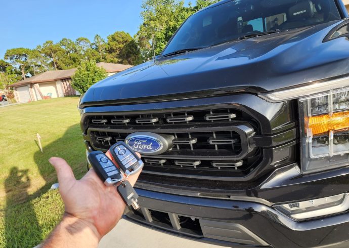A Locksmith holding a key to a Ford F-150 pickup truck.