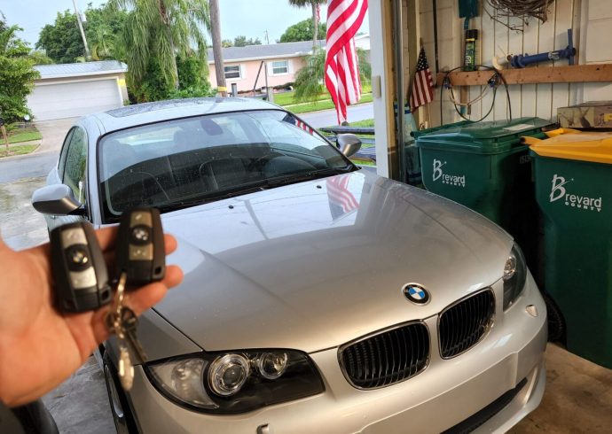 A locksmith holding a key to a bmw car in a garage.