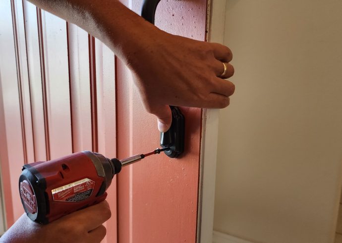 A person using a drill to open a door.