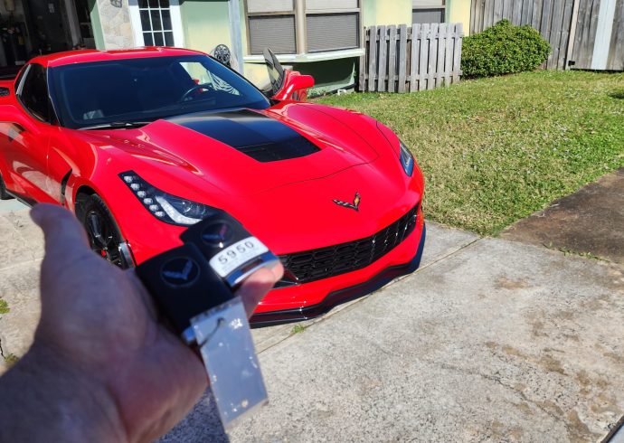 A person holding a key to a red sports car.