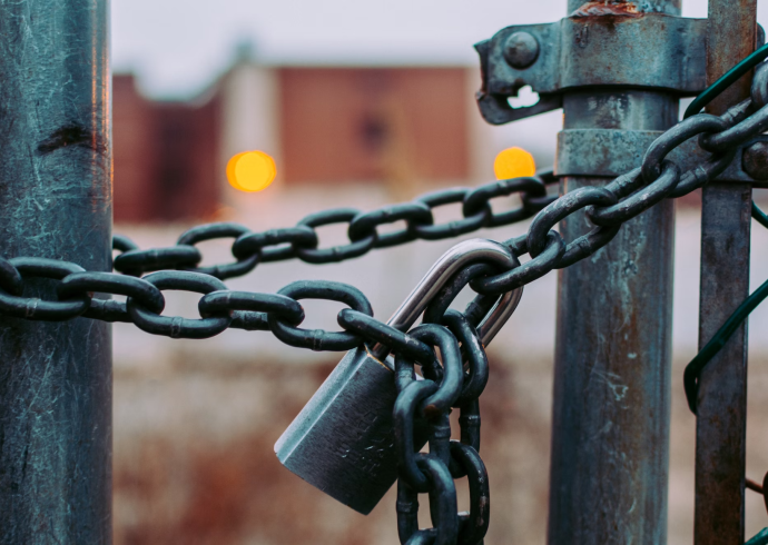 A padlock is attached to a chain link fence.