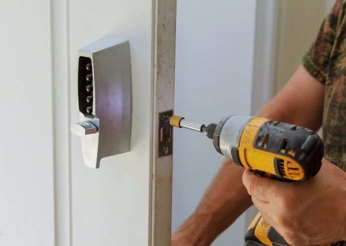 A man using a drill to open a door.